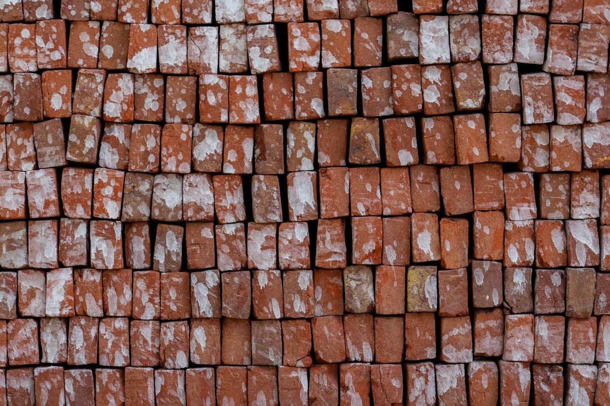 Tijolos cerâmicos vermelhos empilhados em paletes no estoque